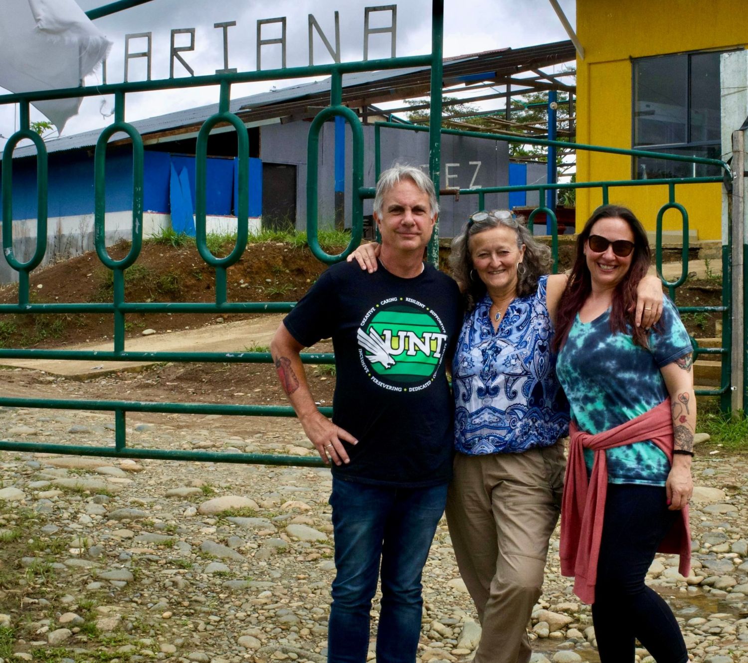 From left to right, Dr. James Meernik, Dr. Kimi King, and Dr. Jacqueline DeMeritt pose in front of a sign that says Mariana